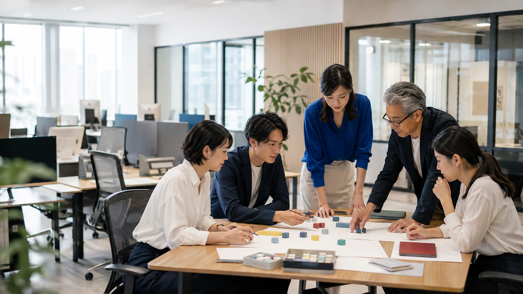 明るいオフィスでカラフルなブロックを囲みワークショップを行うチーム